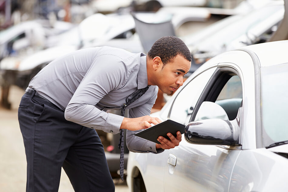 photo of an insurance adjuster reviewing the damage and information of a vehicle involved in a car accident in edmonton where injuries were sustained