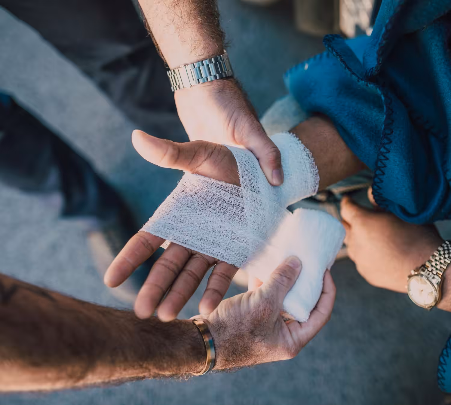 photo of a hand and wrist injury from an accident, the victim being helped by bystanders at the accident scene